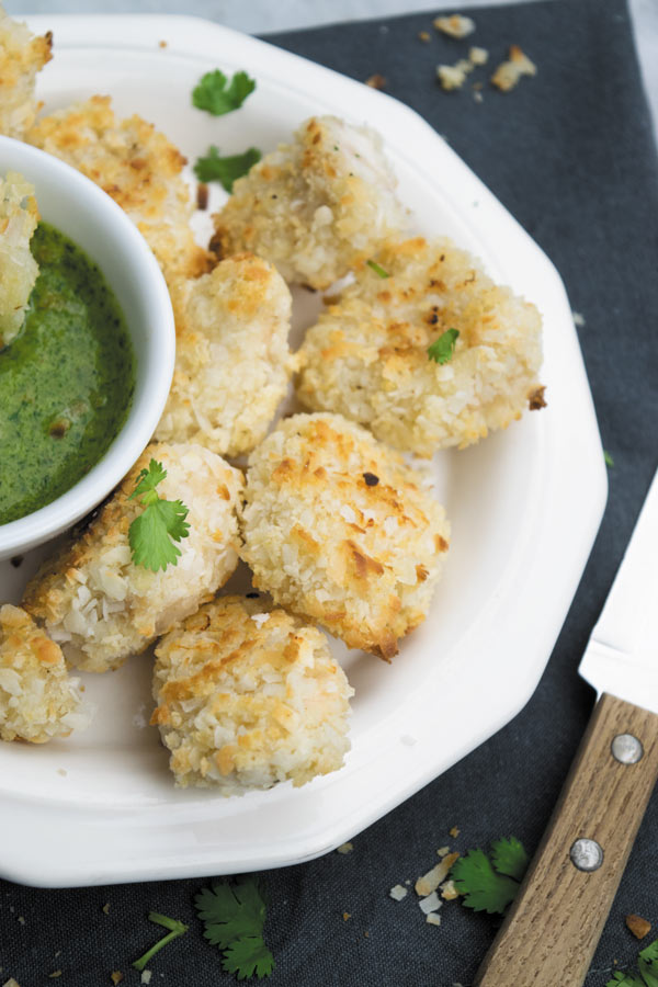 Crunchy Baked Coconut Chicken Bites - Crunchy baked coconut chicken, slightly on the sweeter side served with a spicy cilantro dipping sauce. A great way to make a delicious quick dinner!